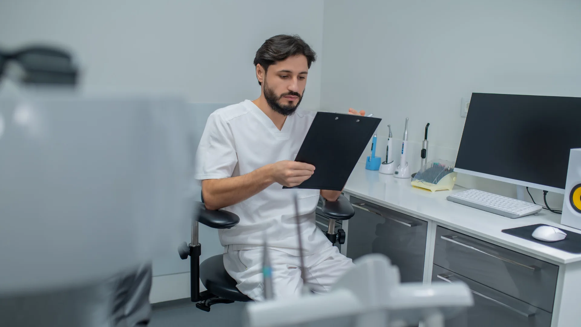 SEO para dentistas - Odontólogo en uniforme blanco revisa historial clínico en consultorio odontológico - seoexit